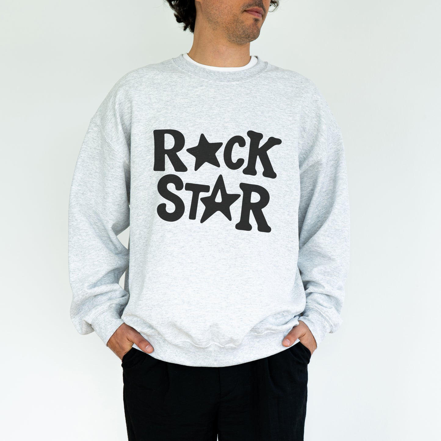 A man wearing a grey sweatshirt with the text "ROCK STAR" printed on it.