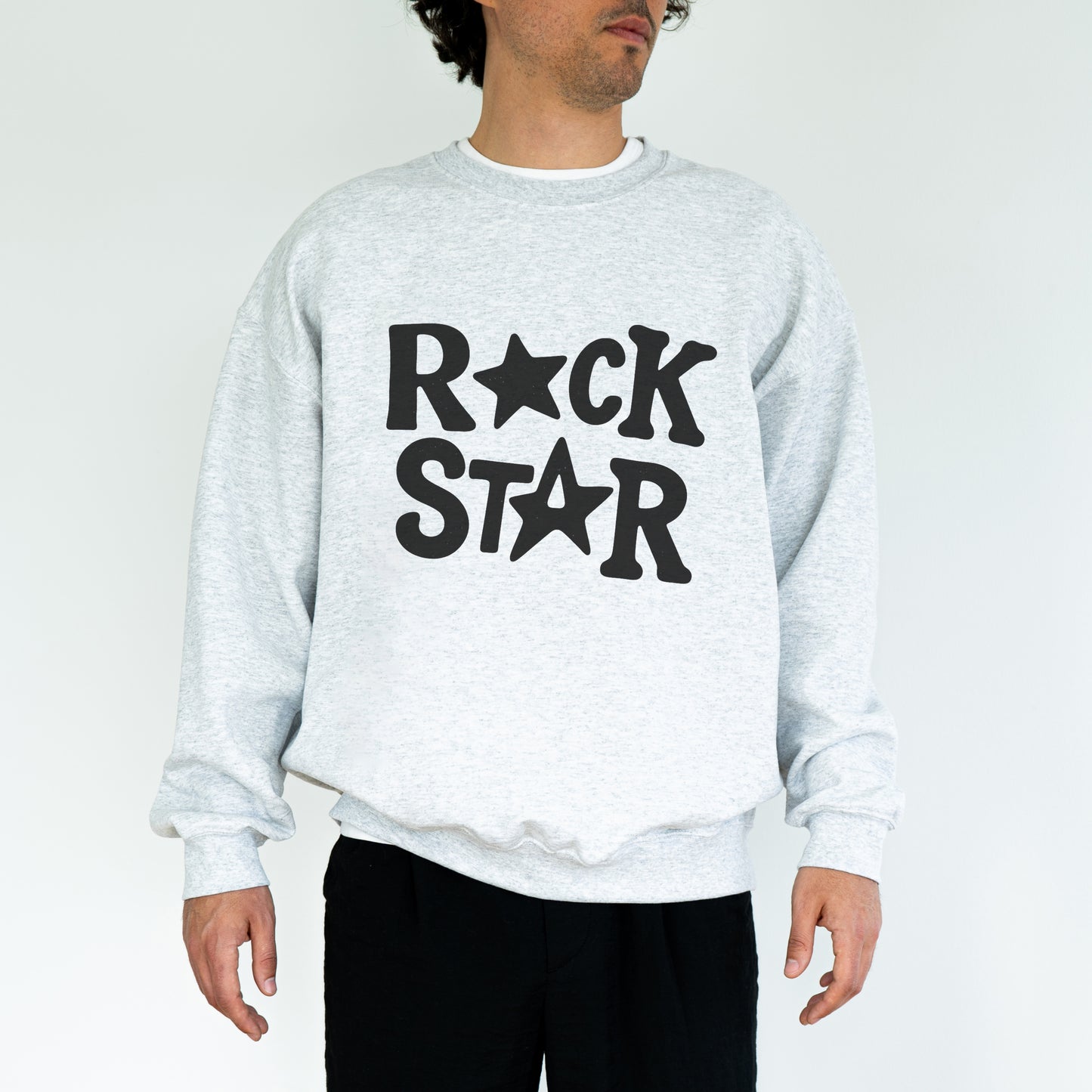A man wearing a grey sweatshirt with the text "ROCK STAR" printed on it.