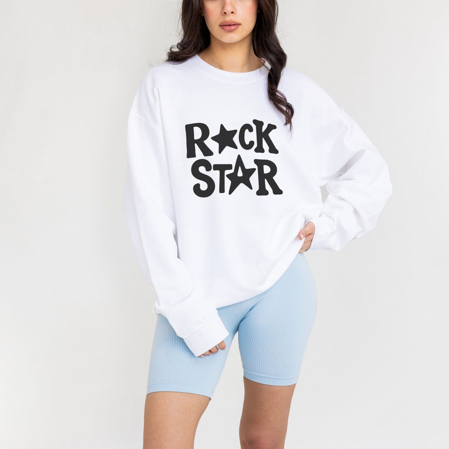 A woman wearing a white sweatshirt with the text "ROCK STAR" printed on it.