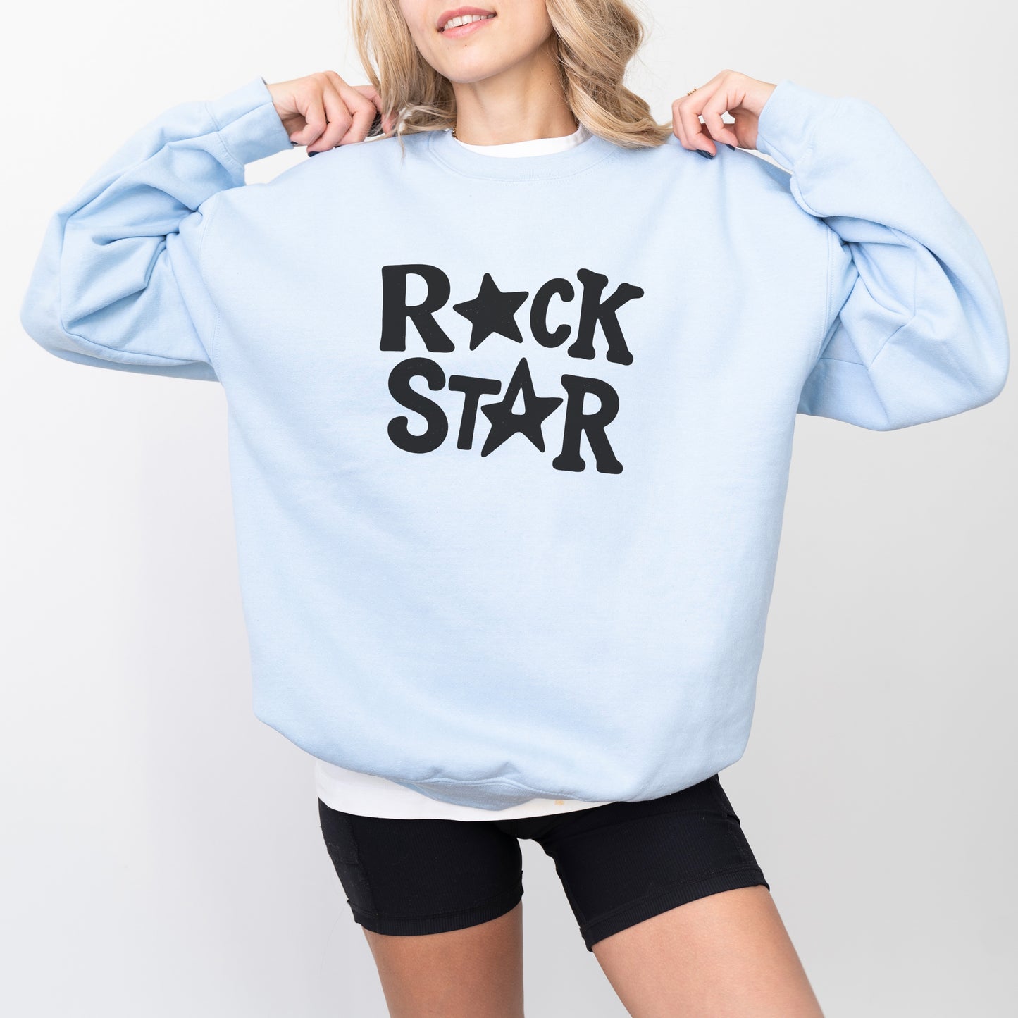 A woman wearing a light blue sweatshirt with the text "ROCK STAR" printed on it.