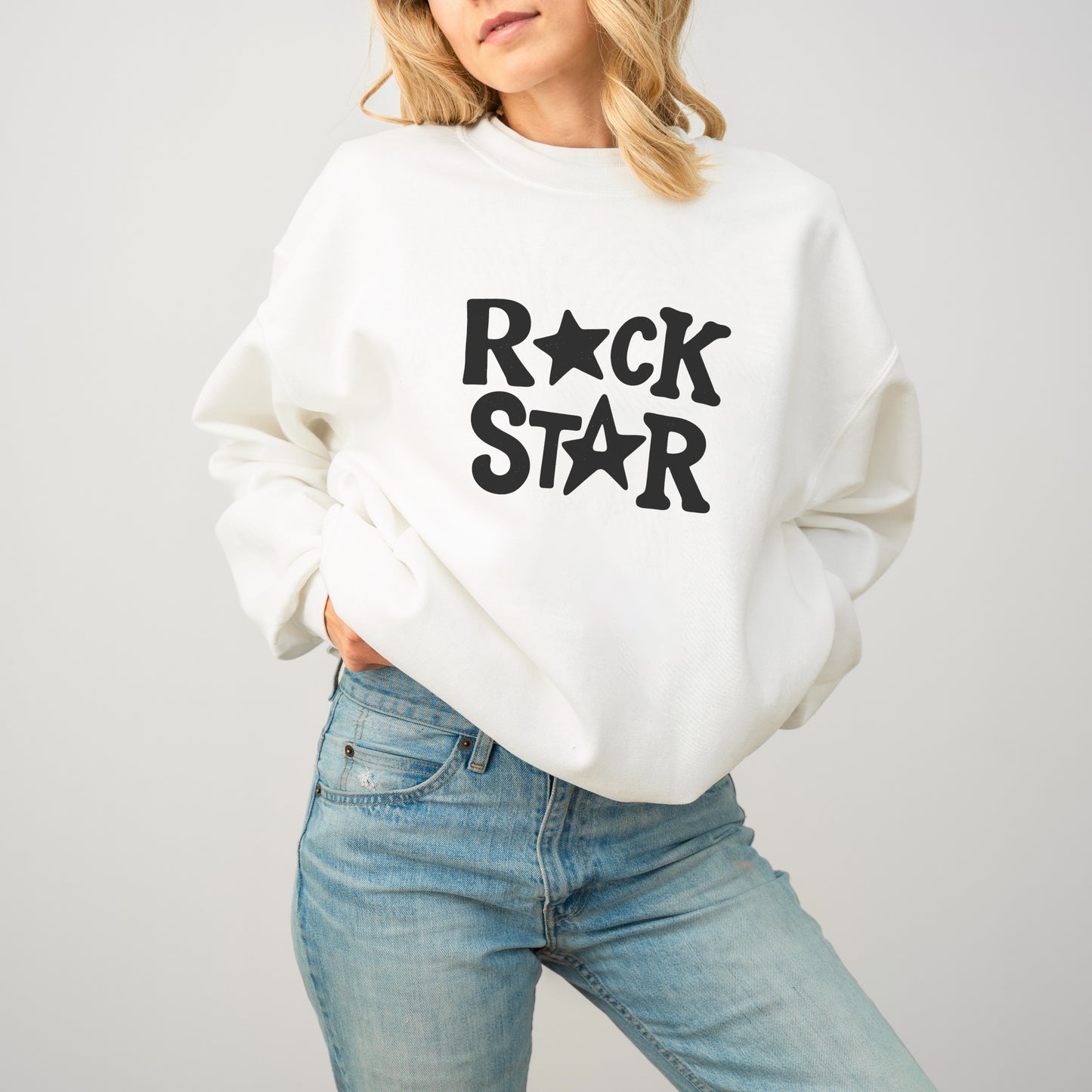 A woman wearing a white sweatshirt with the text "ROCK STAR" printed on it.