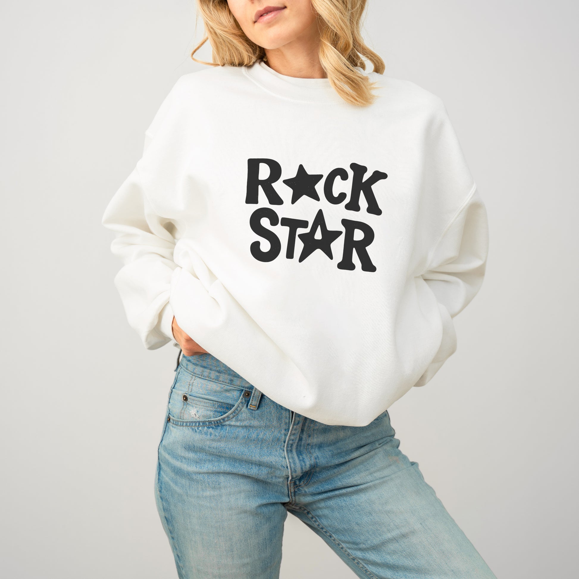 A woman wearing a white sweatshirt with the text "ROCK STAR" printed on it.